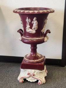 lot 98 image: Tall burgundy vase with Roman figures and lion heads at the handles. Base included